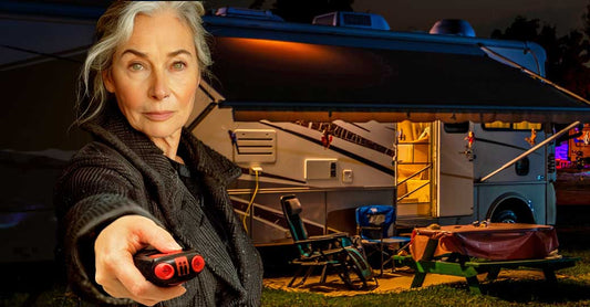 An older woman stands in front of an RV parked at a camp sight at night. She's holding an AIIRO® non-lethal device in her hand, aiming it towards the camera.